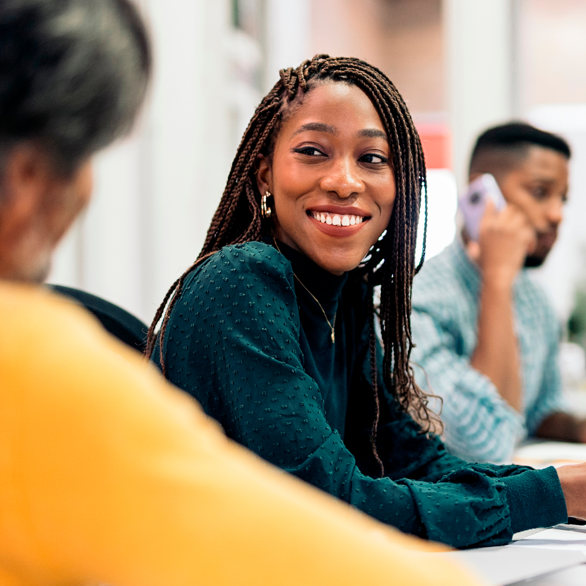 Mujer sonriente en una reunión de trabajo, promoviendo conexión y colaboración en equipo.